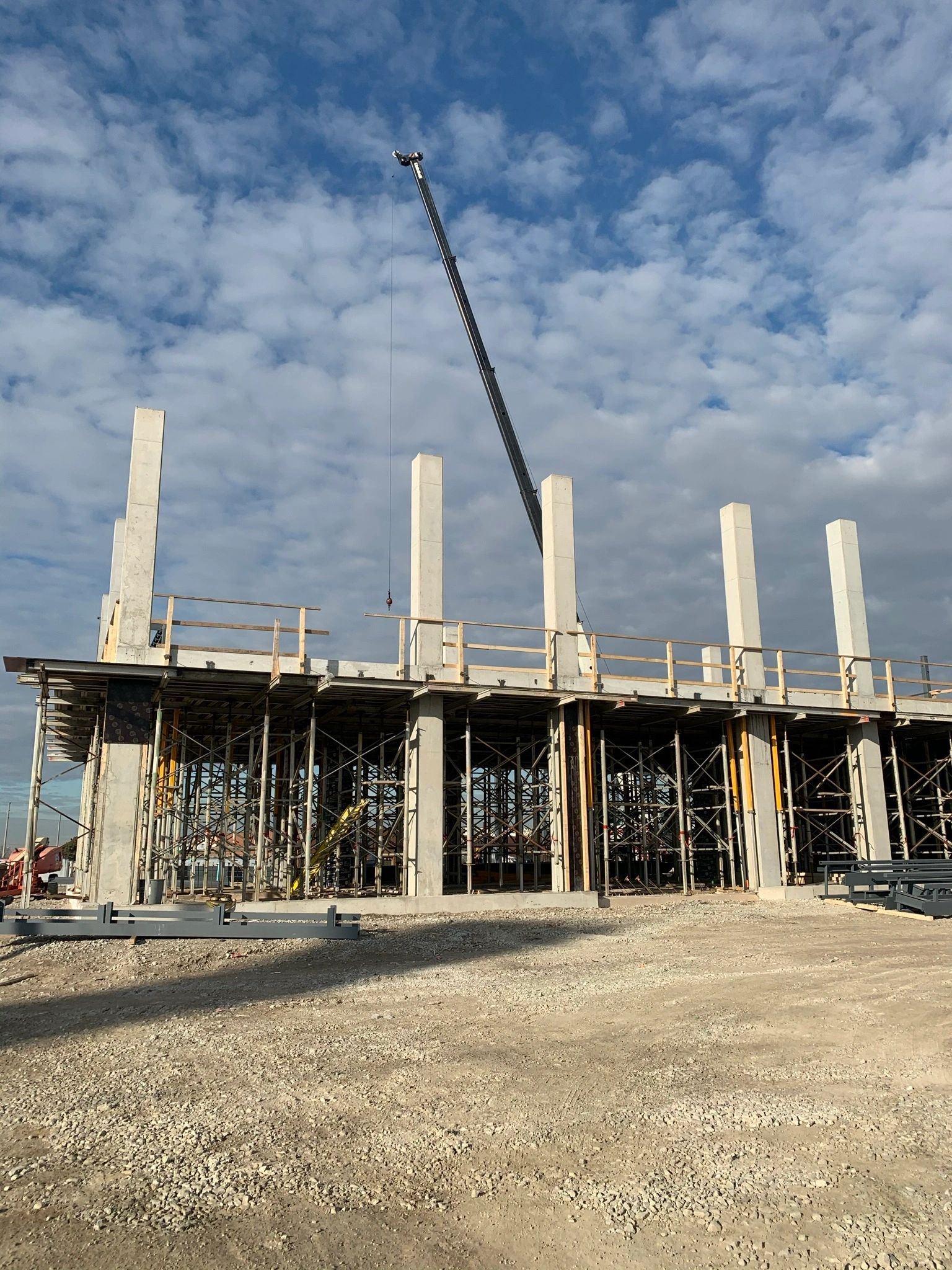 Concrete columns and shoring rising from a slab under a crane