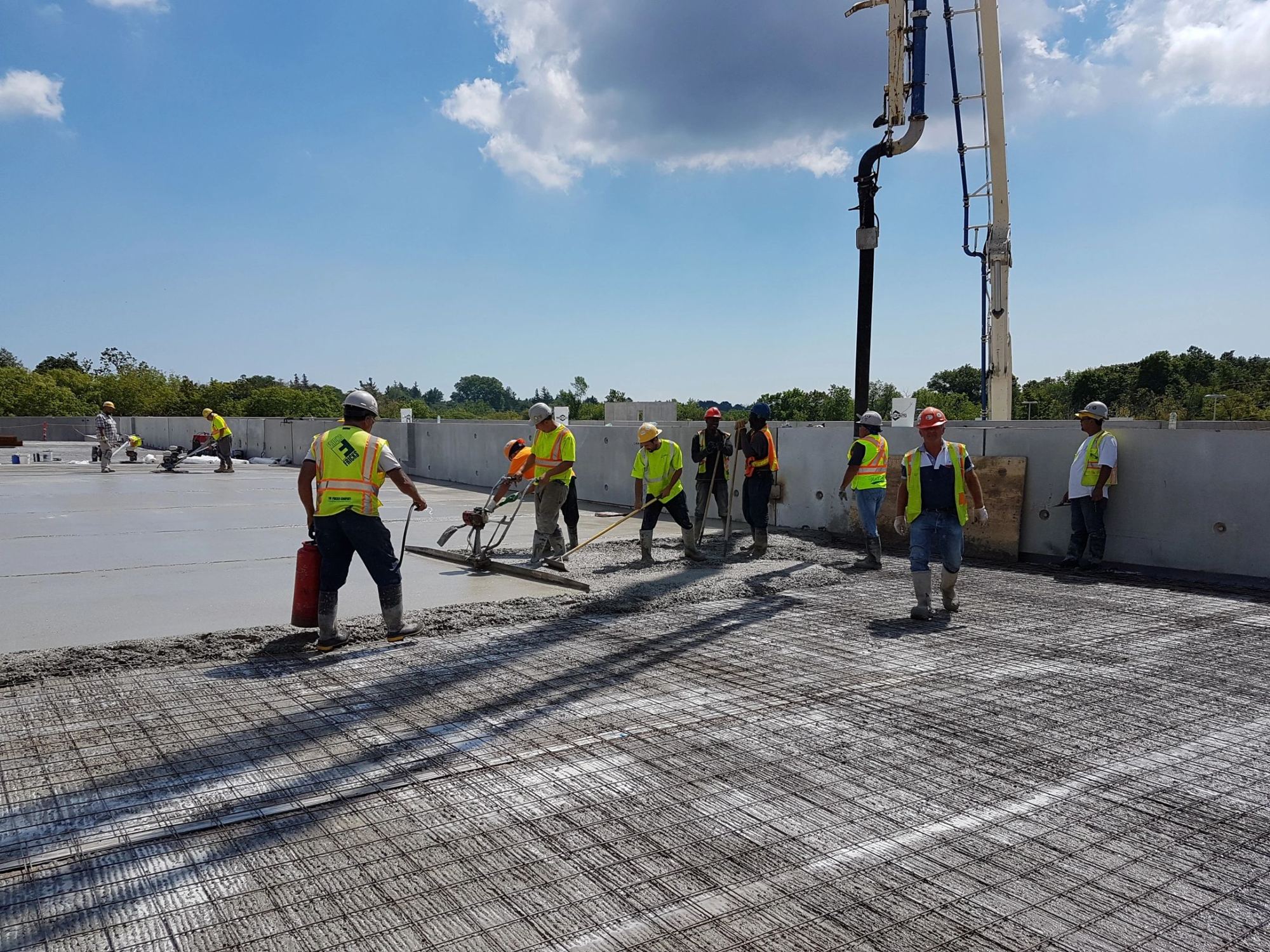 A United crew placing concrete over steel mesh while a pump boom feeds the pour