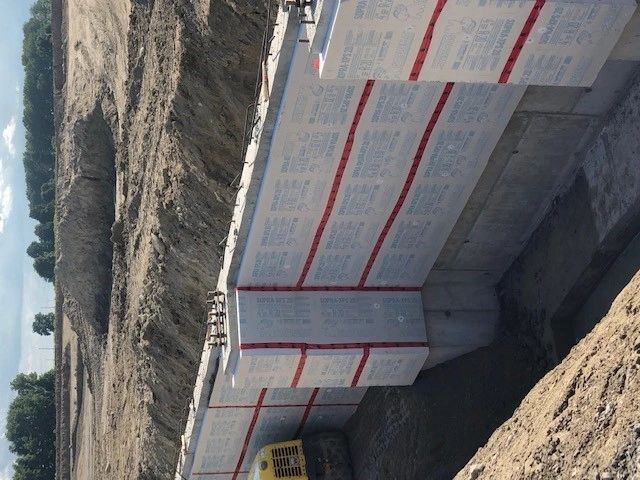 Insulated concrete forms stacked into a foundation wall at the edge of an excavation