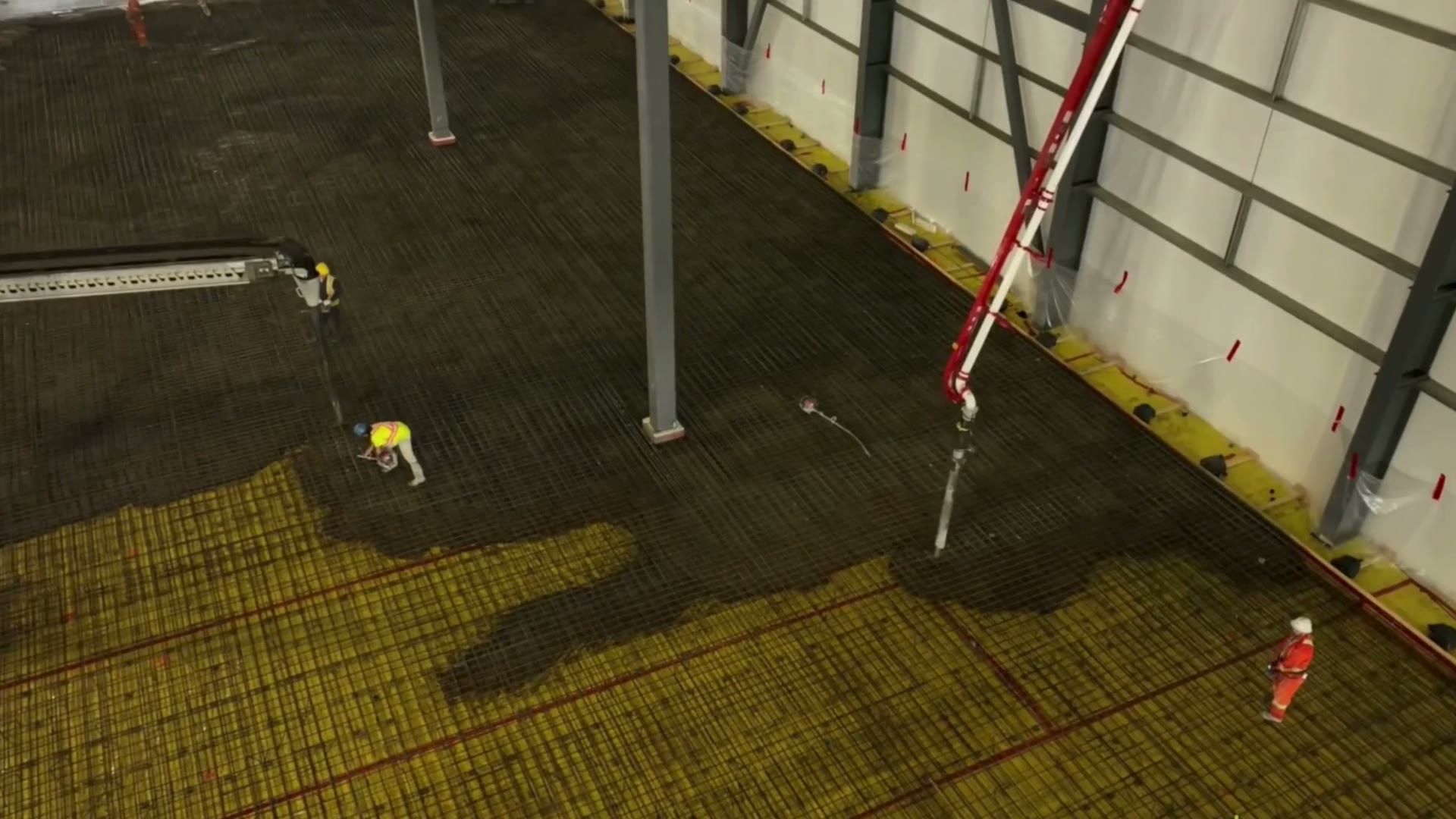 A red pump boom reaching across a warehouse to place concrete