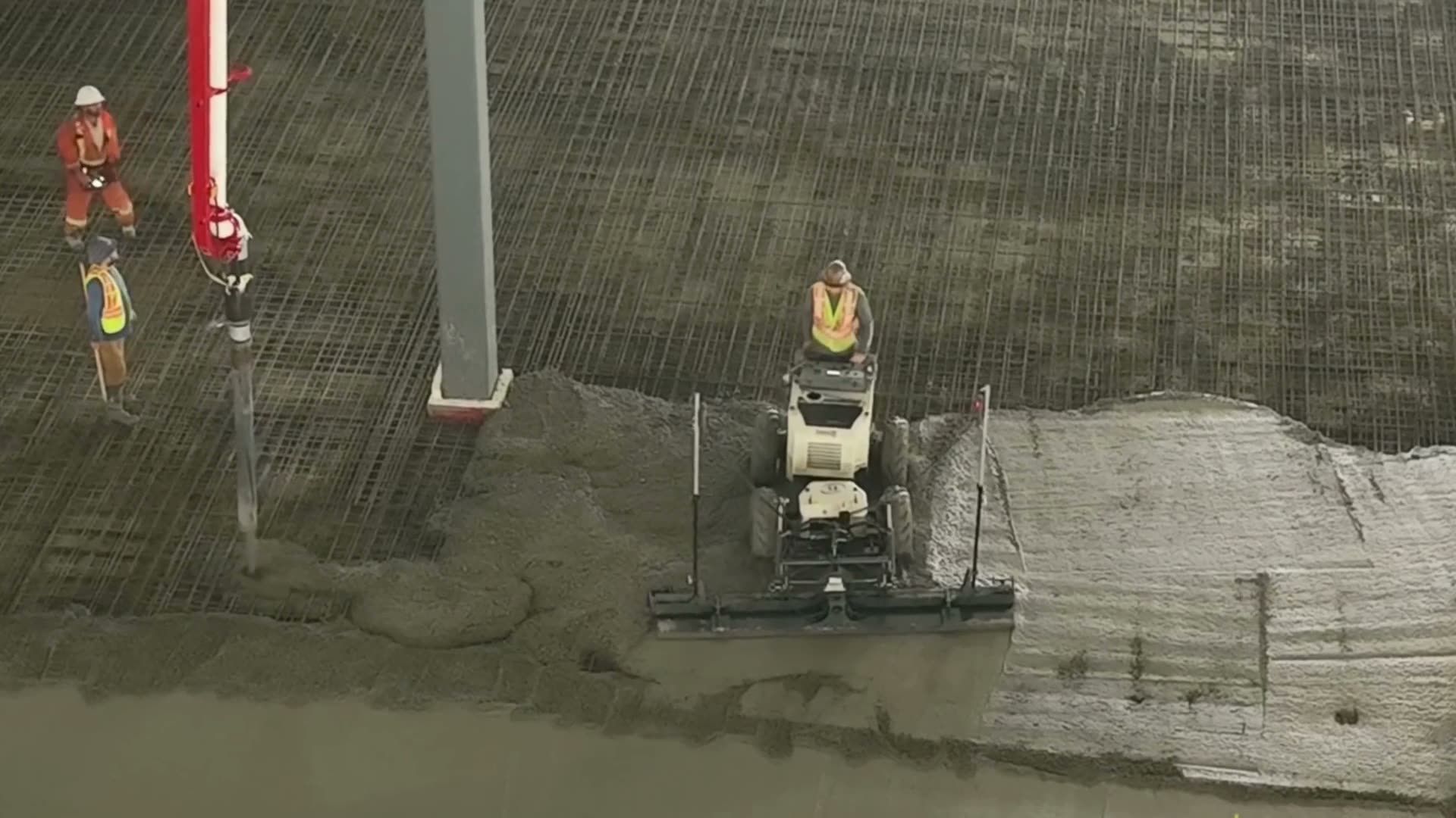 A crew in high-visibility vests placing concrete under a pump line