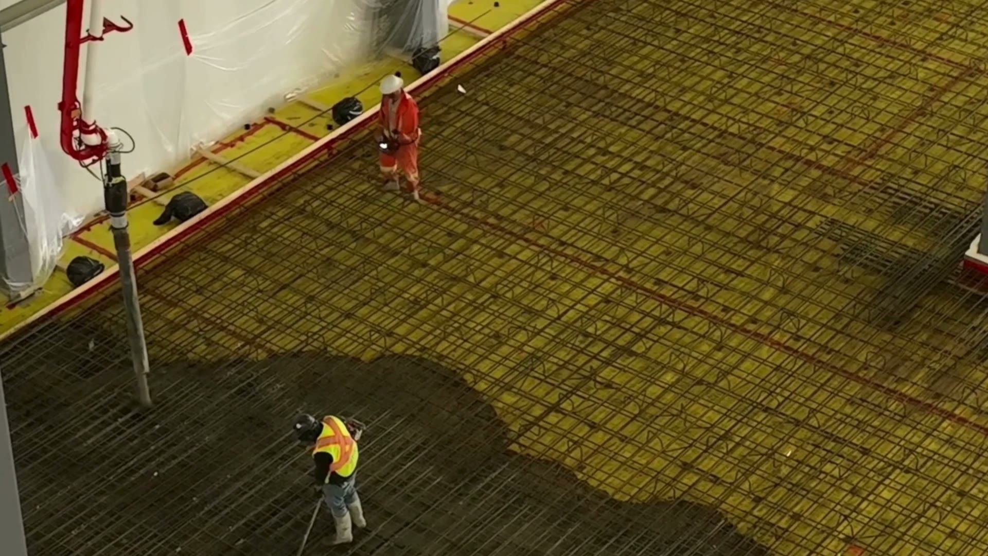 Concrete spreading across a rebar mat on insulation, seen from above