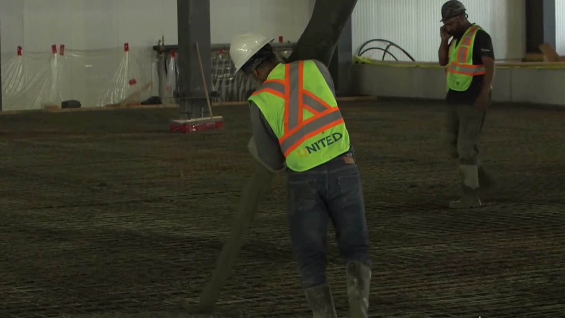 A United finisher, the company name on the back of his vest, working fresh concrete