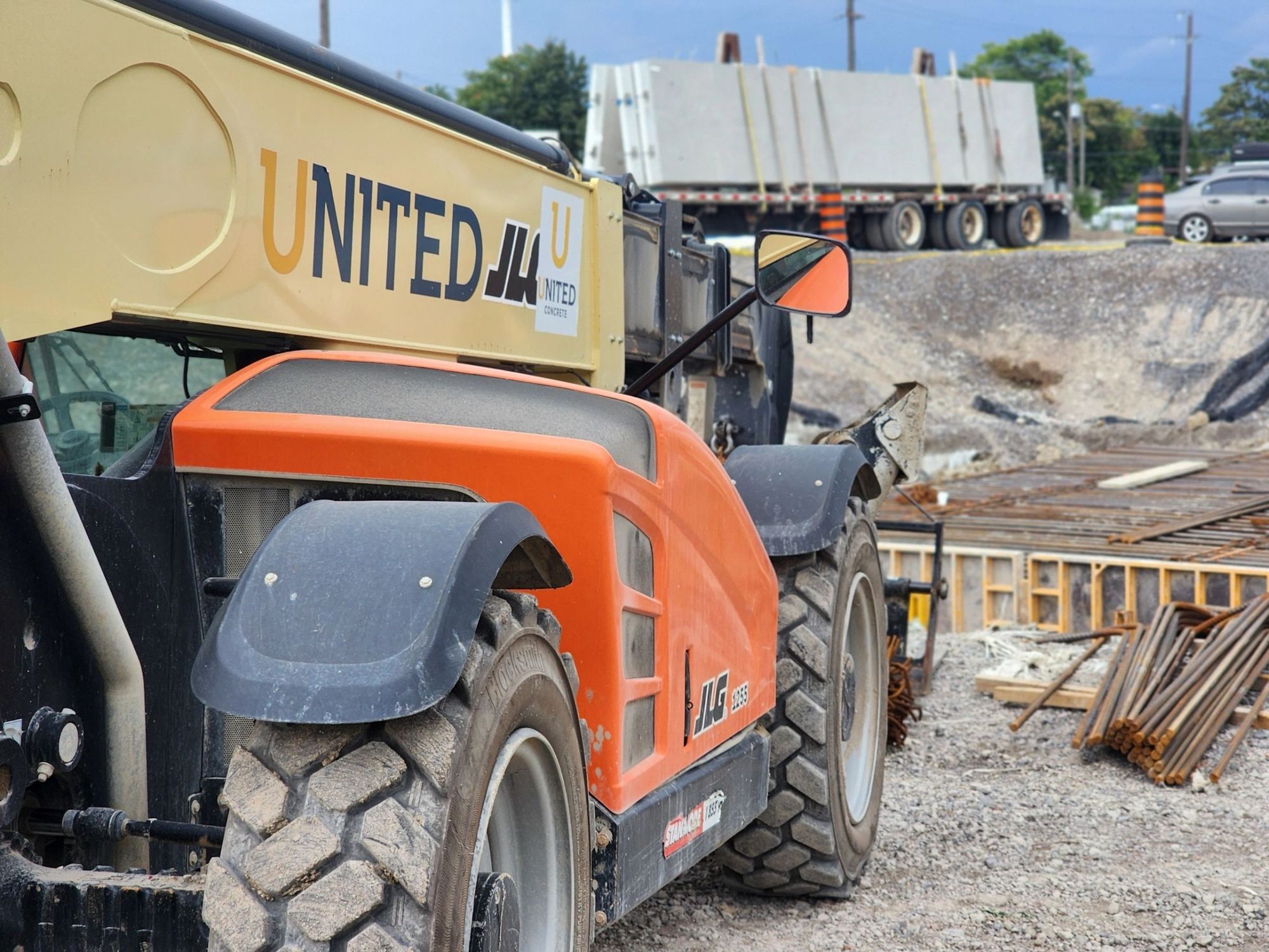 A telehandler with the UNITED name on its boom working beside formwork and rebar