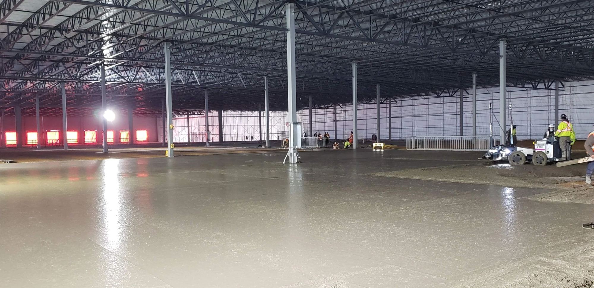 Freshly placed concrete gleaming across the floor of a new steel-frame warehouse